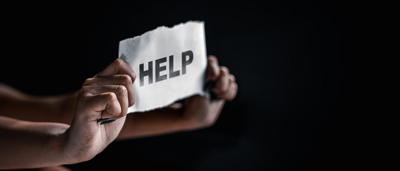 Woman holding paper with text asking for help